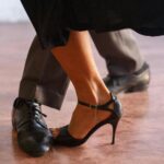 Close-up of a couple dancing tango, highlighting elegance in black shoes and high heels.